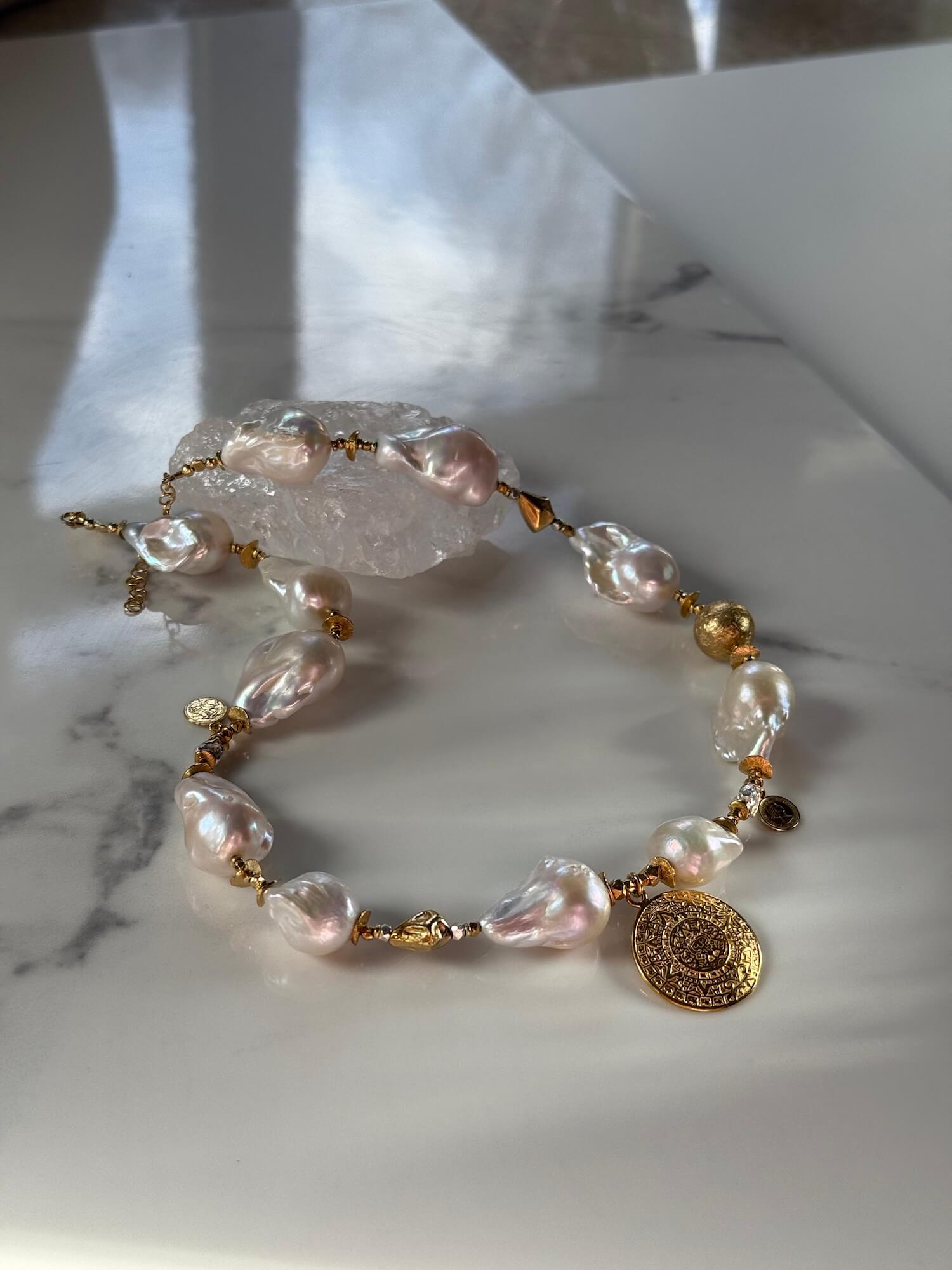 Zbliżenie naszyjnika z białych pereł barokowych i pozłacanej zawieszki