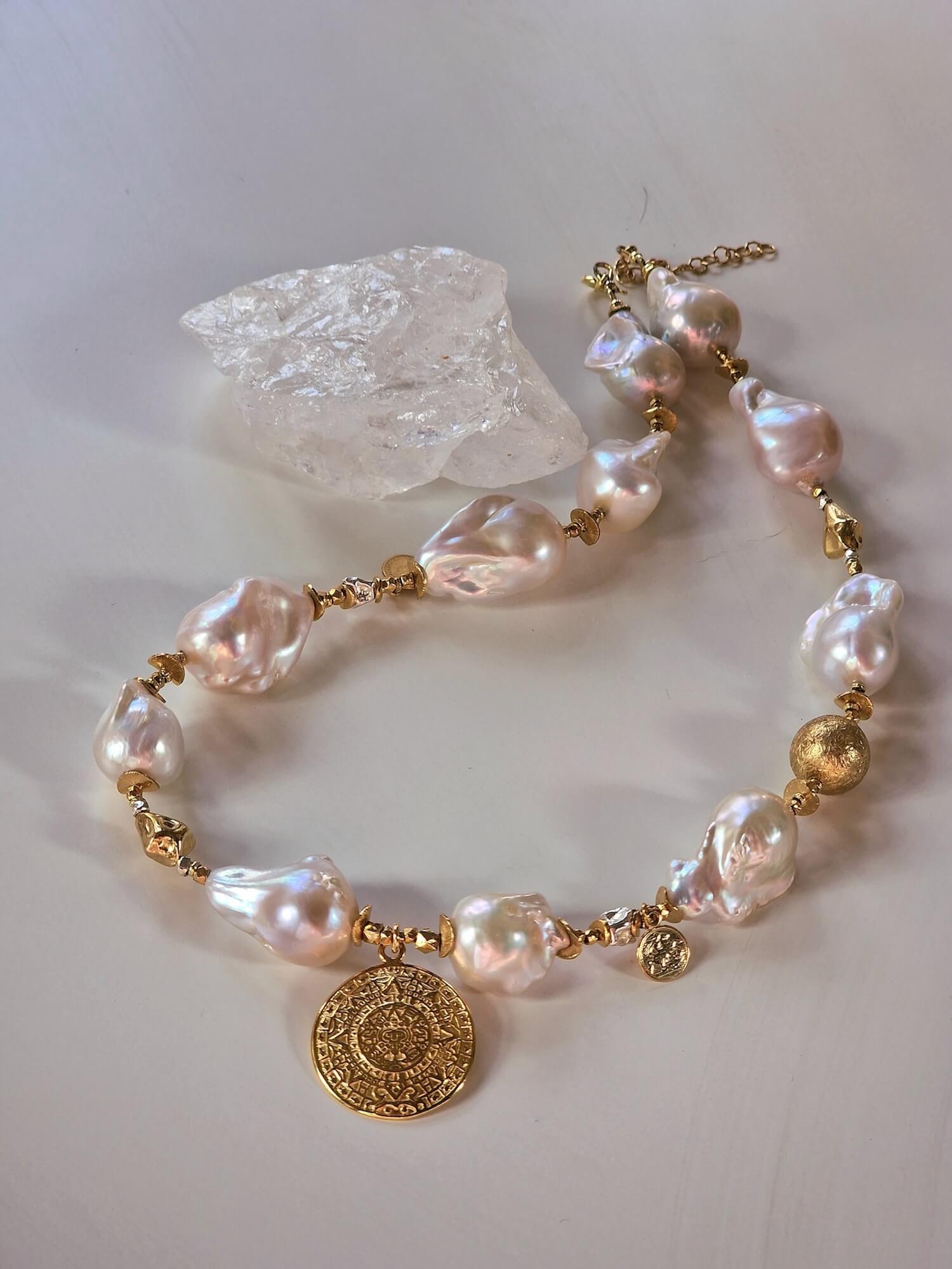 Zbliżenie naszyjnika z białych pereł barokowych i pozłacanej zawieszki