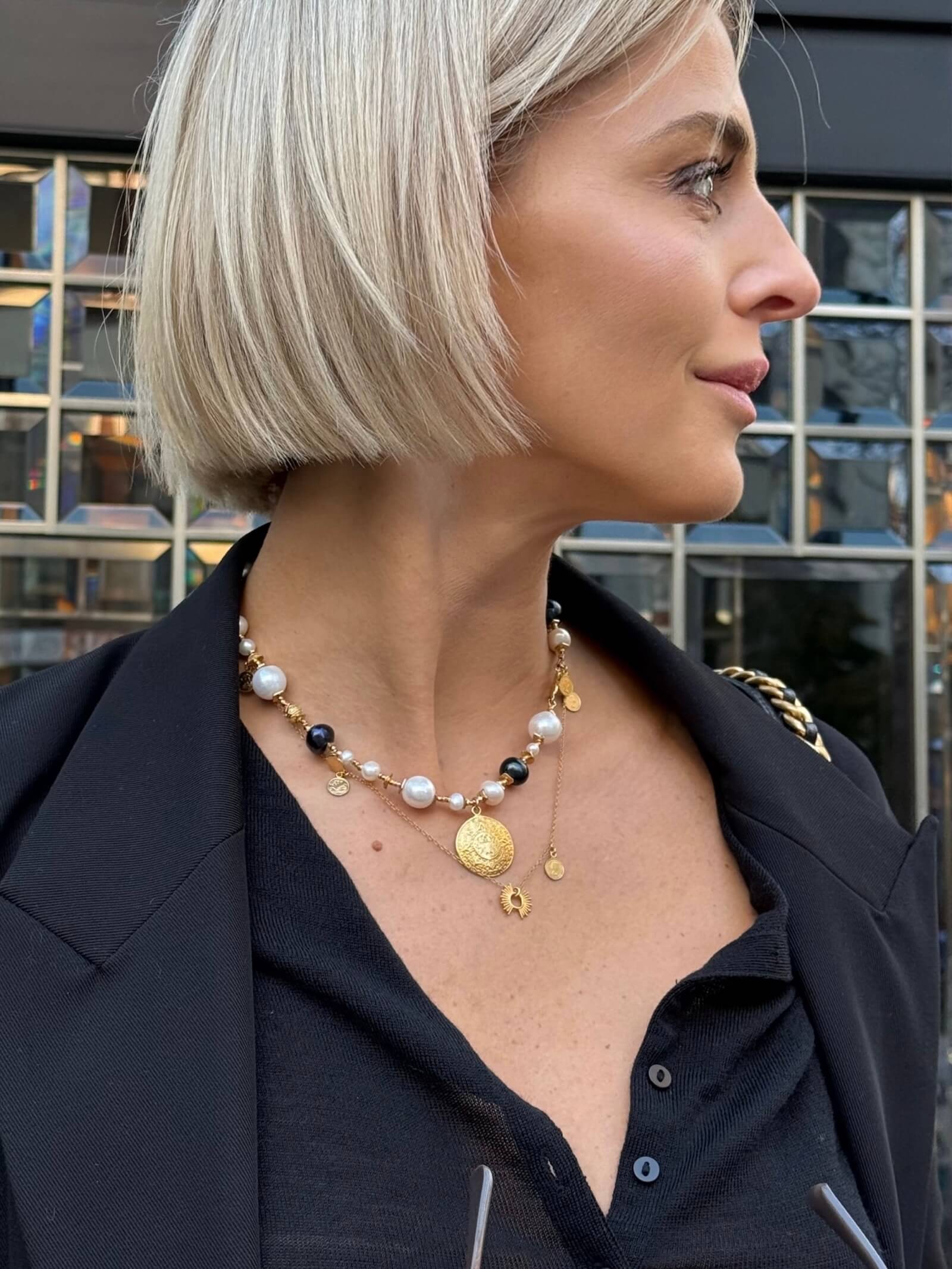 Detal białych i czarnych pereł oraz monety Azteków w naszyjniku