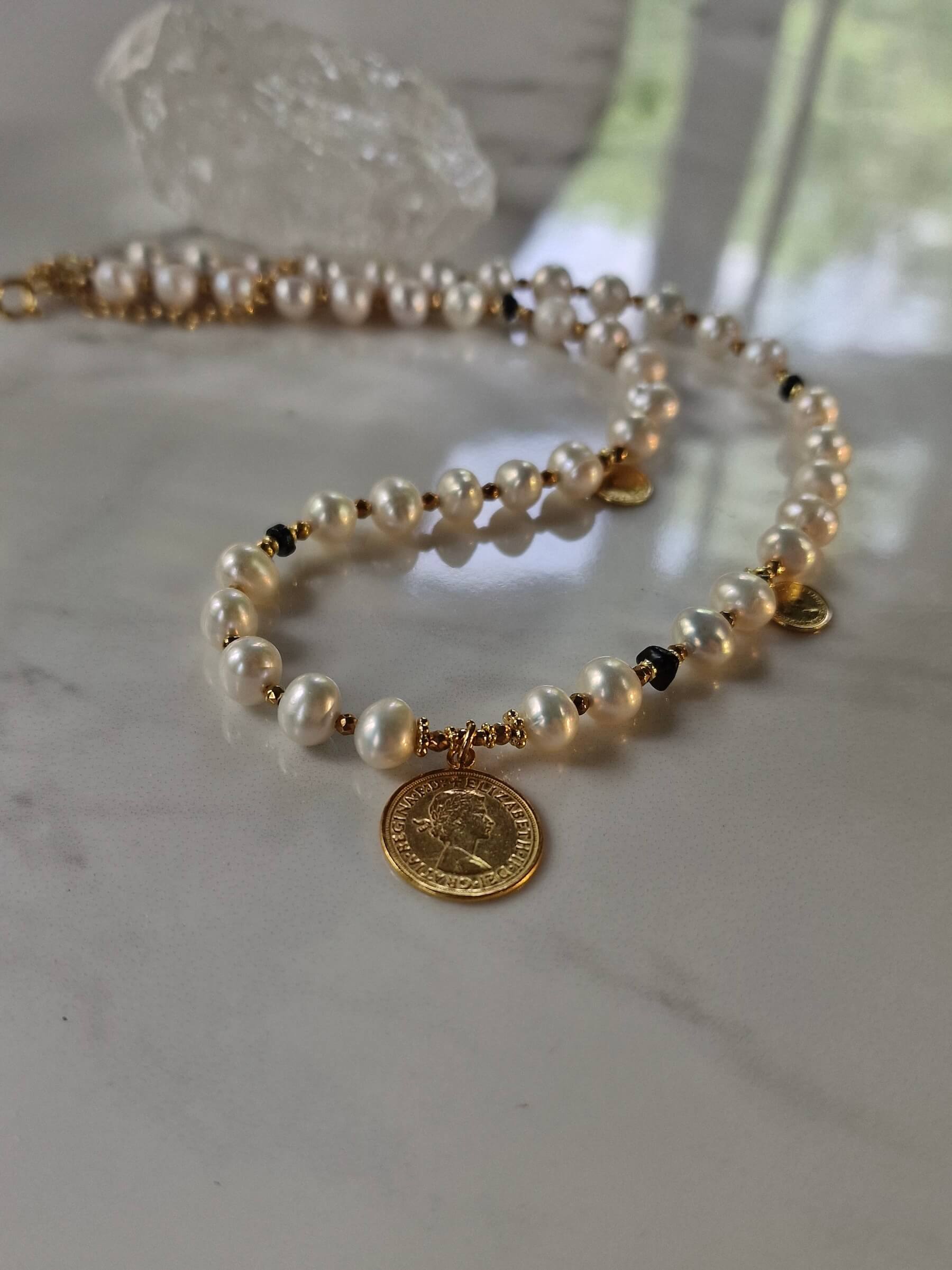 Packshot naszyjnika z naturalnych pereł z monetą