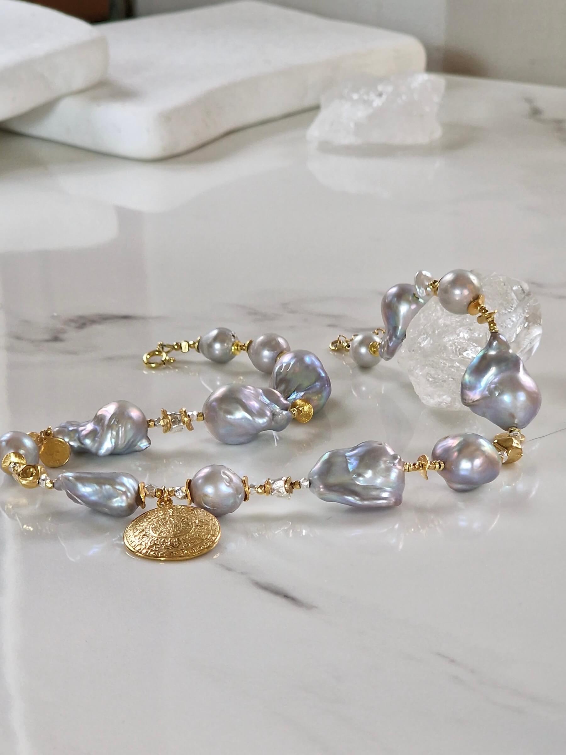 Detal pozłacanej zawieszki i pereł barokowych w naszyjniku